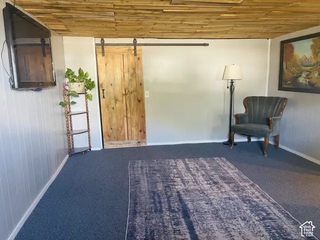 Wood-paneled ceiling with recessed lighting, shiplap wall accents, and a rustic wood barn door