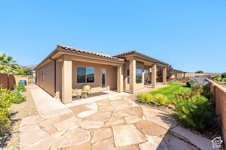 Expansive flagstone patio with a covered outdoor living area, manicured lawn, and mature landscaping