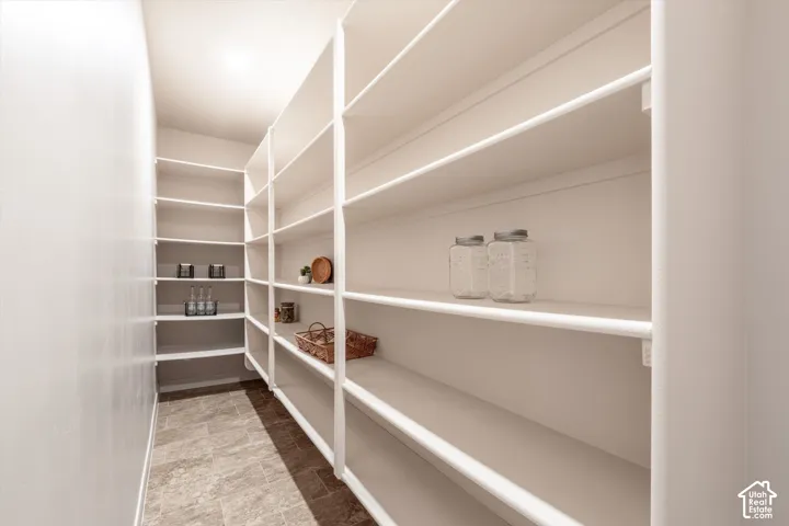 Walk-in pantry featuring extensive white shelving and tiled flooring