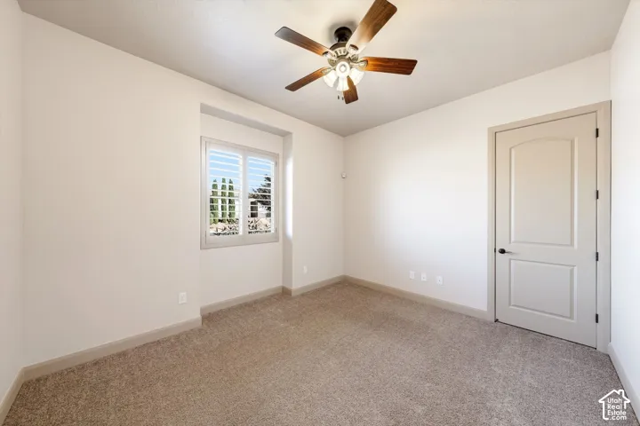 Carpeted flooring, recessed window, white plantation shutters, ceiling fan with integrated lighting, and a paneled door