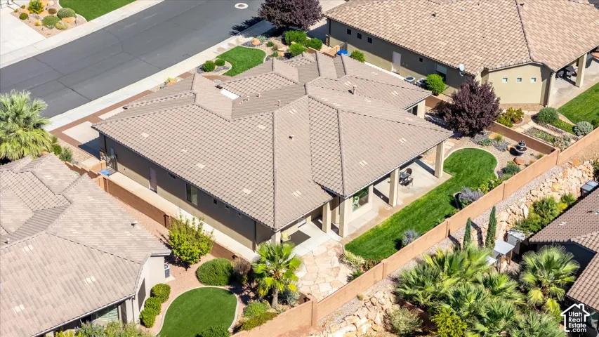 Single-story residence featuring a tile roof, covered patio, stone pathway, and landscaped grounds with mature plantings
