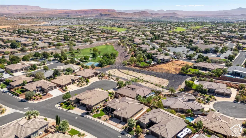 Expansive residential development with numerous single-story properties, visible golf course, and distant mountain backdrop