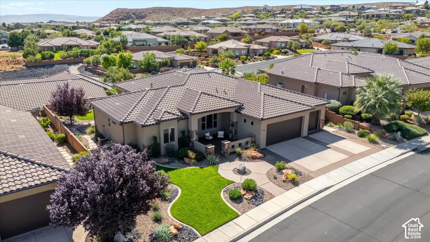 Southwestern style residence featuring a tile roof, an attached two-car garage, and a manicured front lawn with varied landscaping