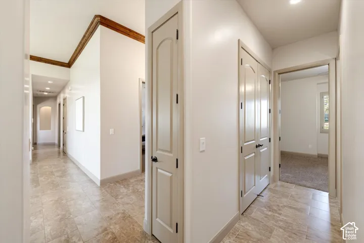 Hallway featuring tile flooring, recessed lighting, and a wood-finish crown molding accent
