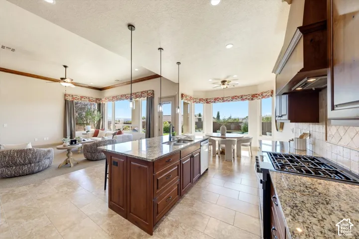 Open concept living space featuring a central kitchen island with seating, dark wood cabinetry, and light-toned granite countertops