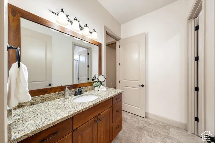 Wood-finish vanity with a granite countertop, undermount sink, and black-finish faucet