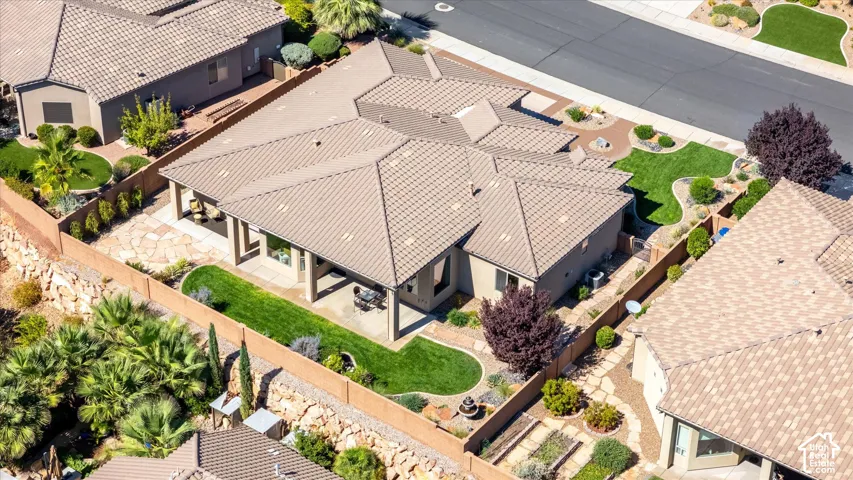 Tile roof architecture, covered patio with flagstone, landscaped yard with manicured lawns, stone retaining walls, and mature plantings