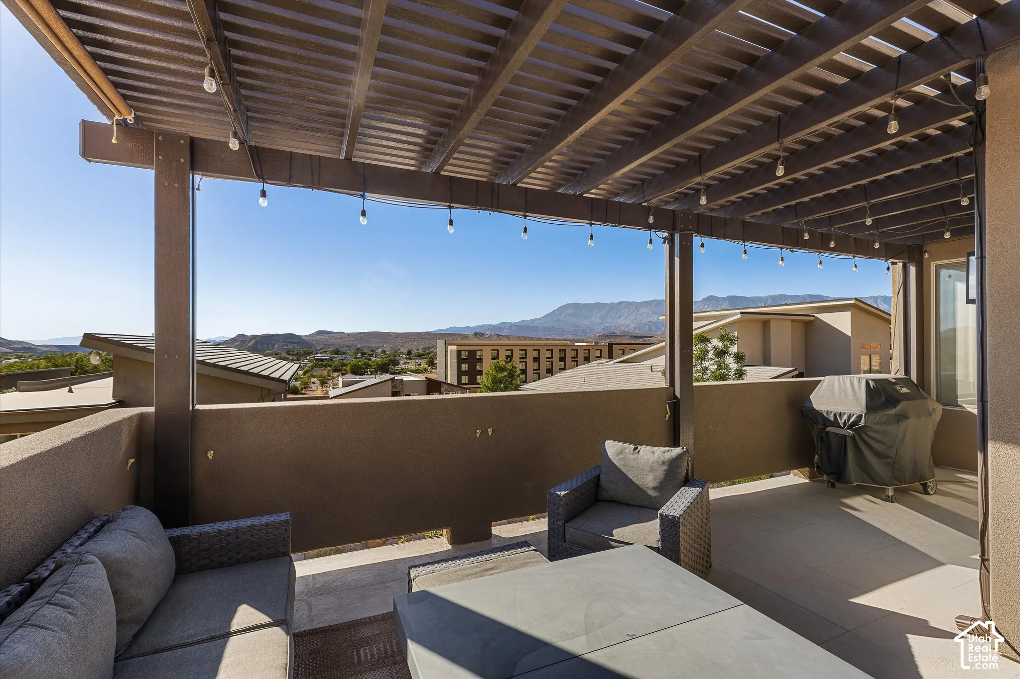 Patio featuring a slatted pergola, concrete flooring, and an exterior wall with a window
