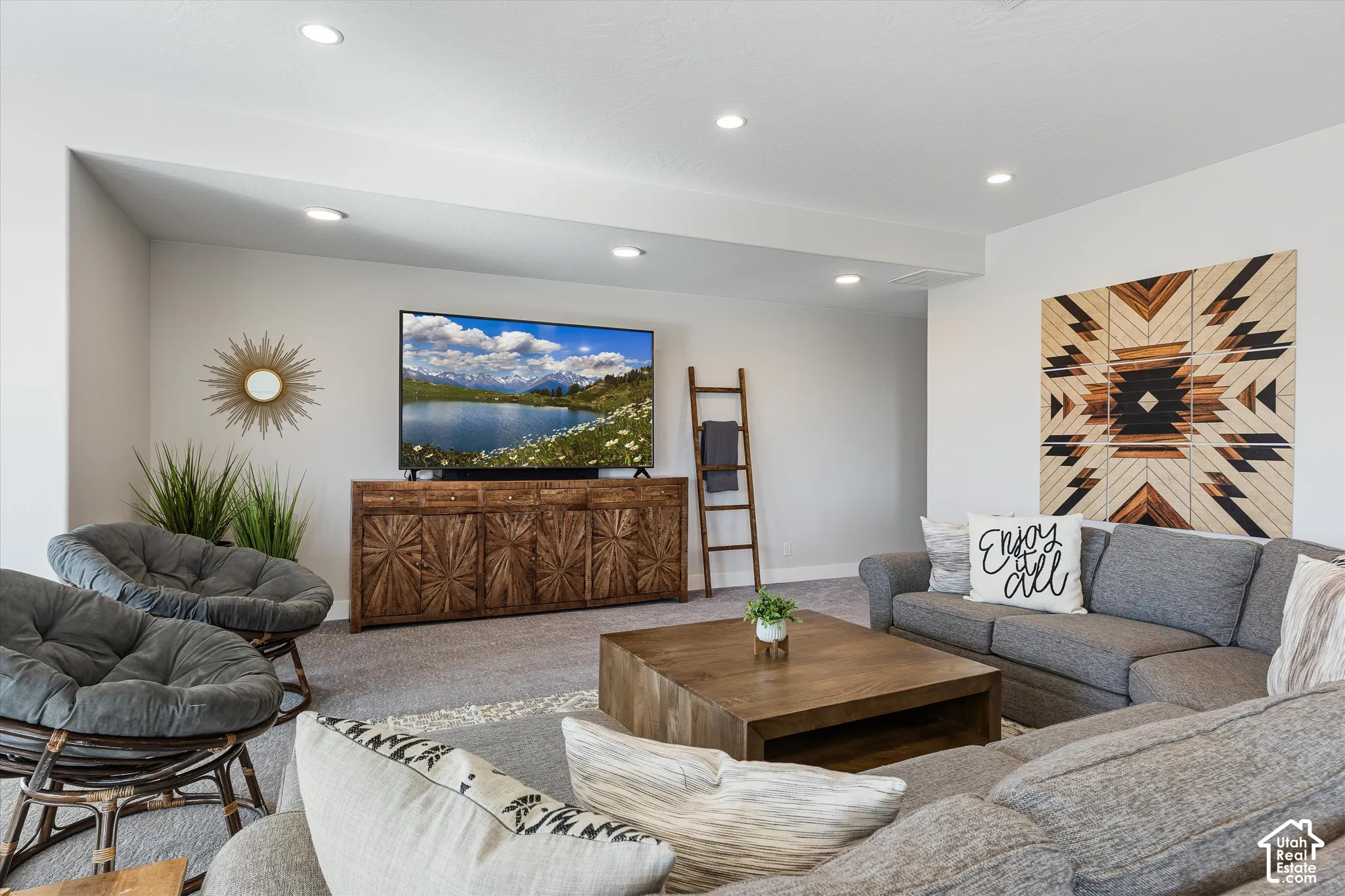 Recessed lighting, wood-finish media console, and neutral wall tones complement the carpeted flooring