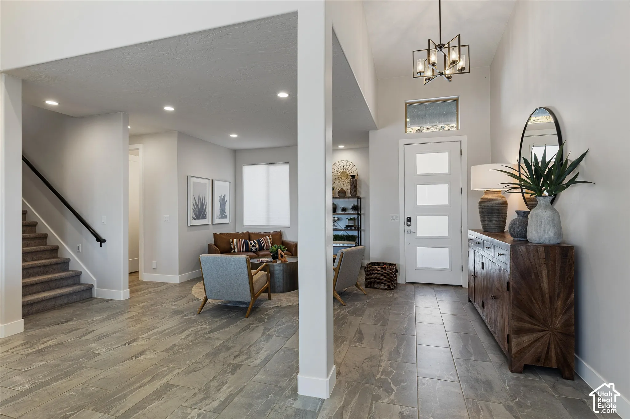 Foyer with high ceilings, contemporary chandelier, and a white entry door with frosted panels