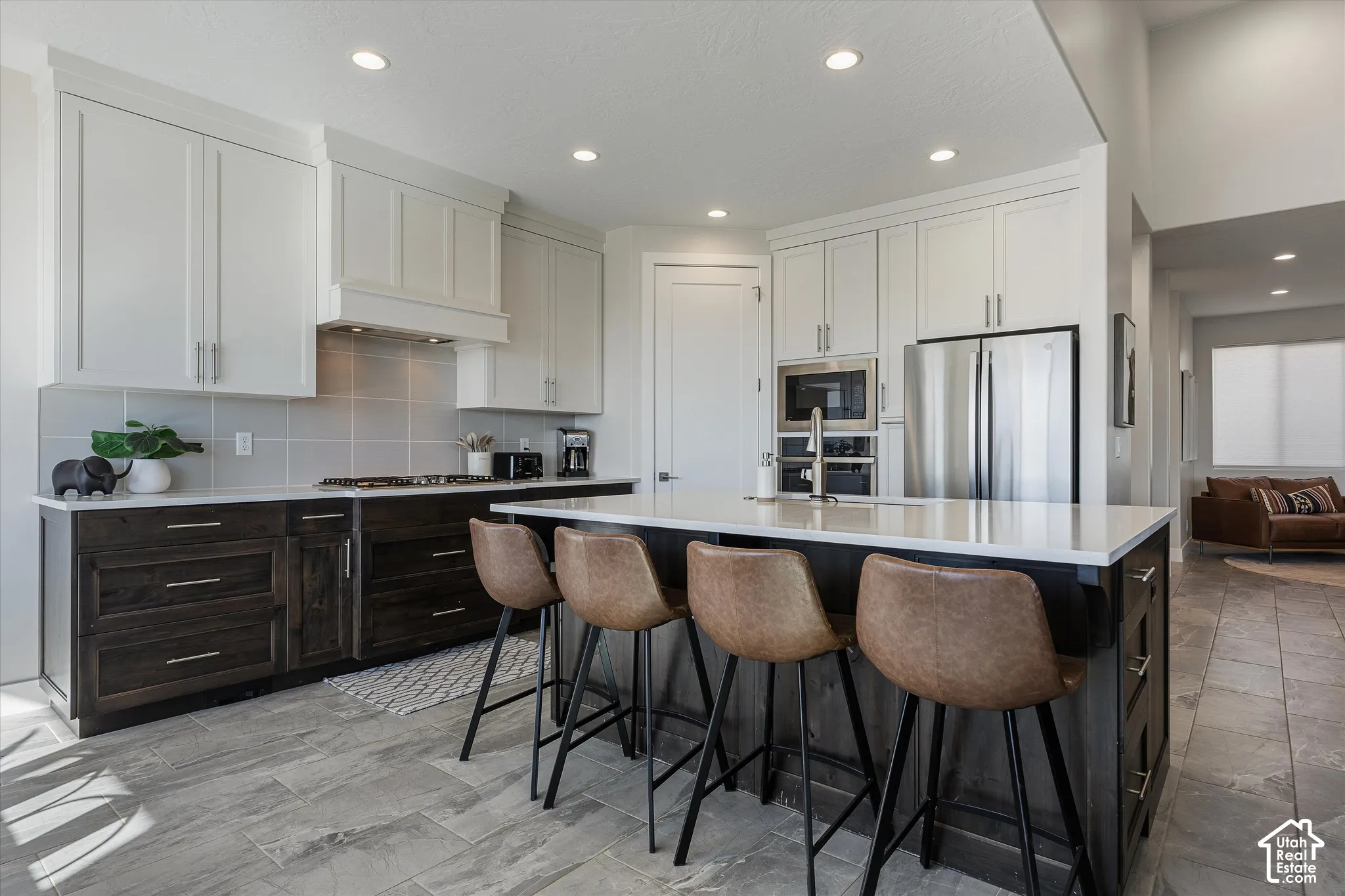 Open-concept kitchen with a large center island, contrasting cabinetry, stainless steel appliances, and tile flooring