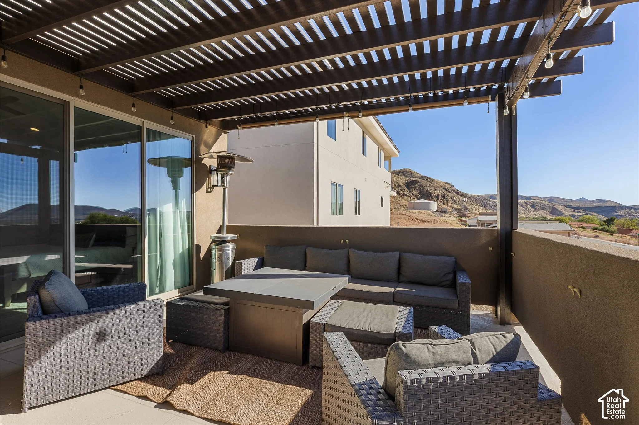Patio with a slatted pergola, integrated lighting, sliding glass doors, and a partial privacy wall