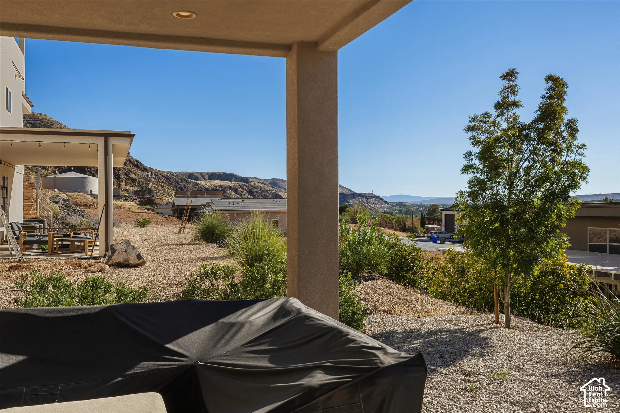 Covered patio with recessed lighting, gravel landscaping, and distant mountain scenery