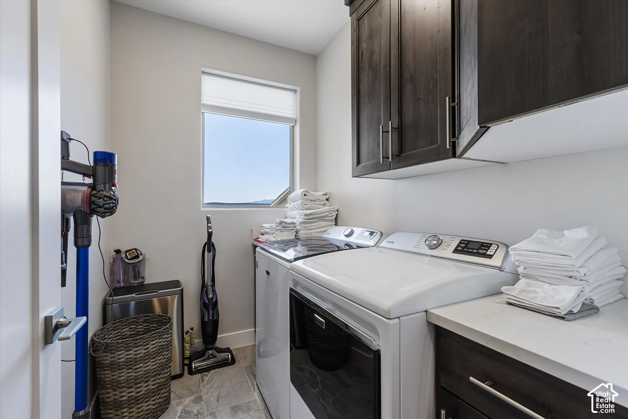 Laundry room featuring upper and lower cabinetry, a built-in countertop, and a window