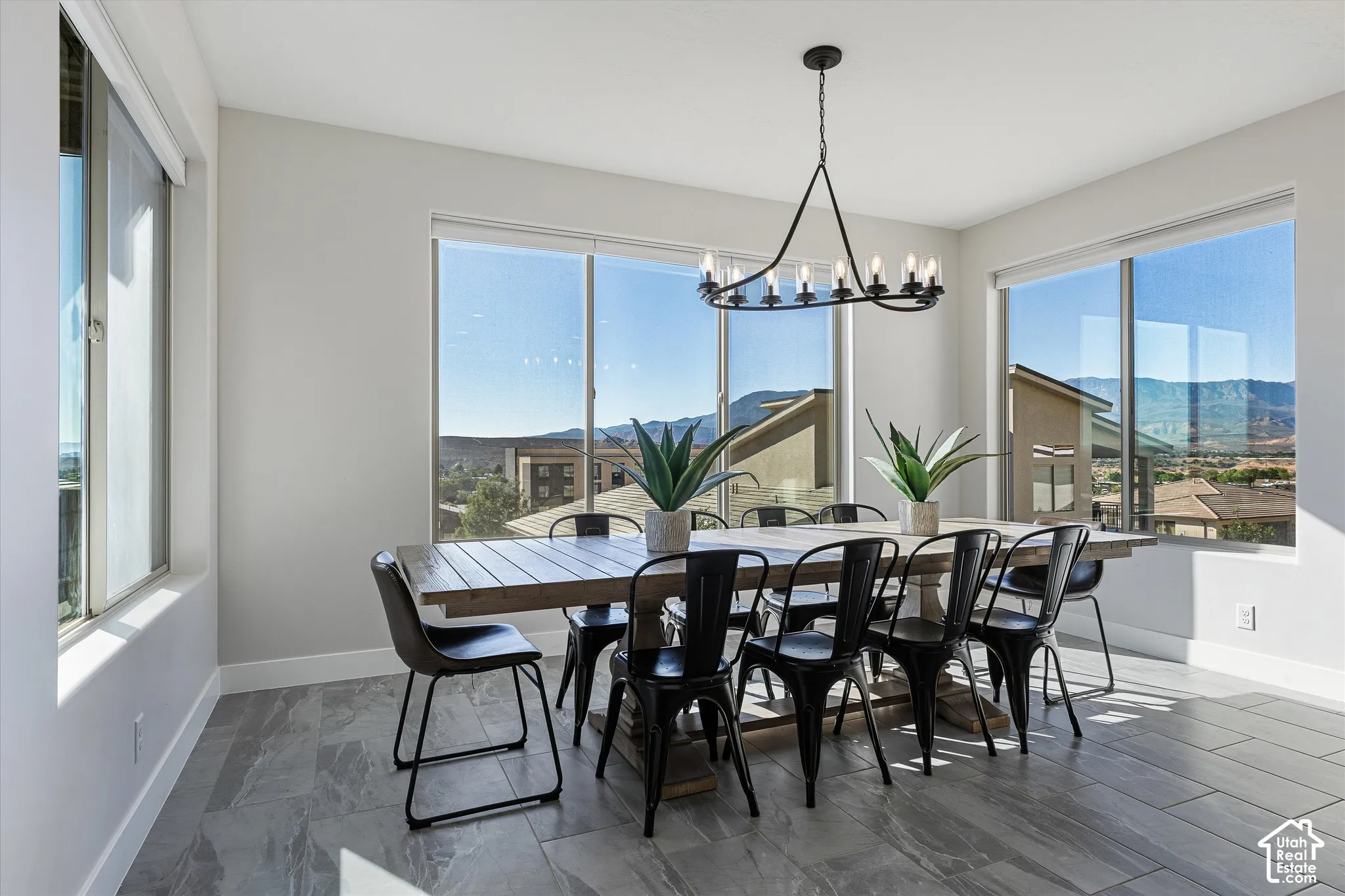 Spacious room featuring multiple windows, a modern chandelier, and tile flooring