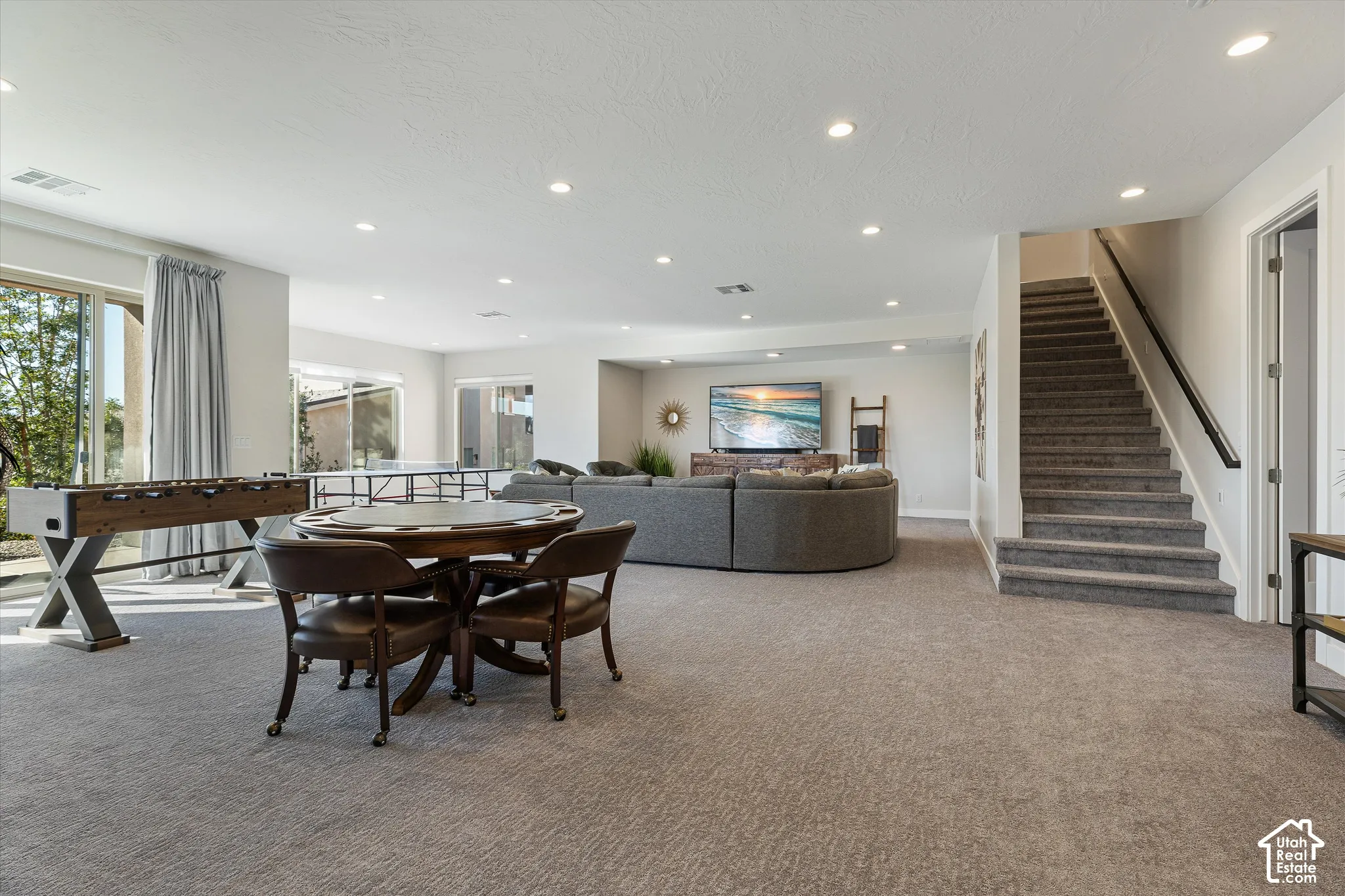 Recessed lighting illuminates a spacious room featuring wall-to-wall carpeting and sliding glass doors