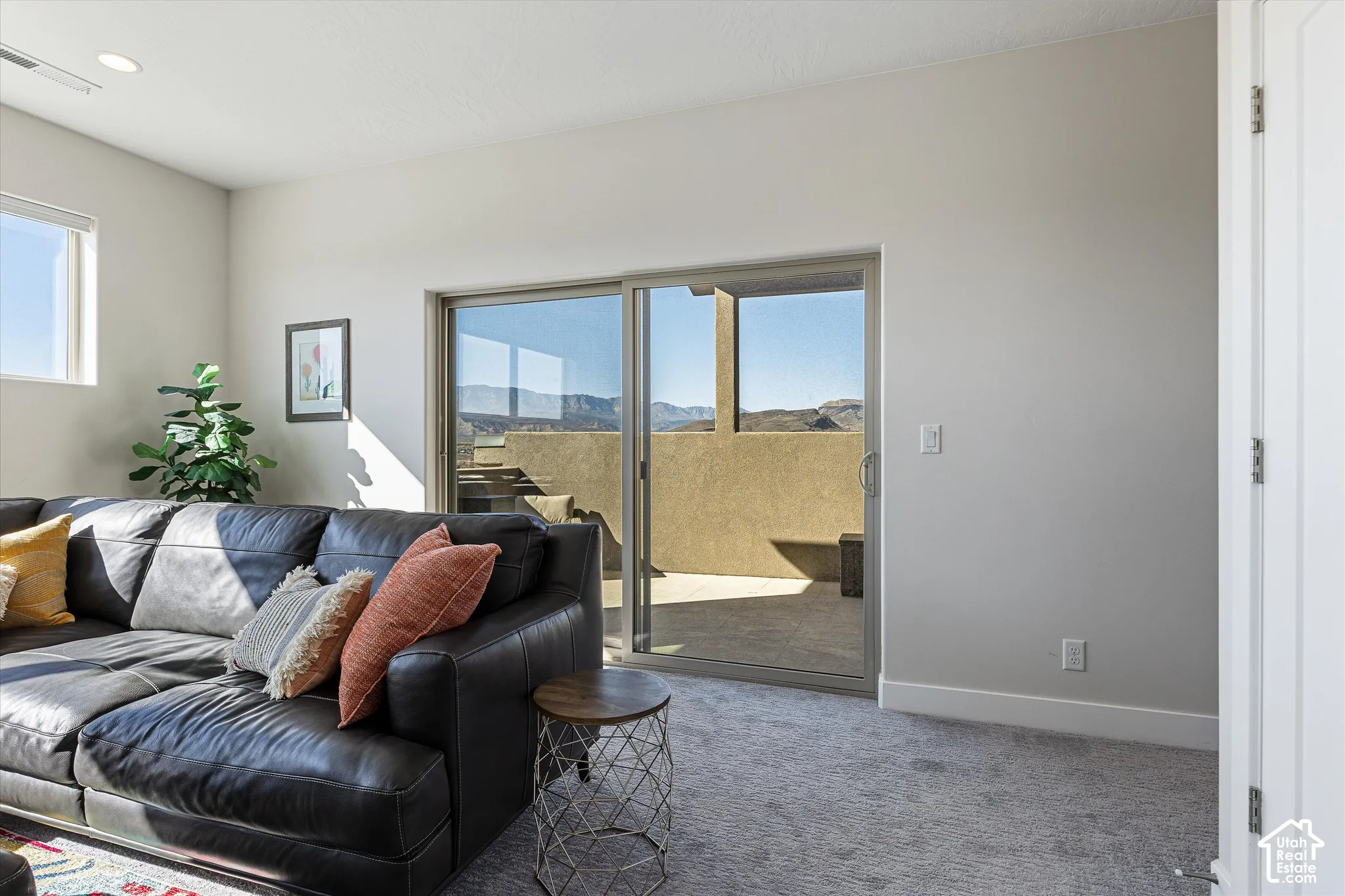 Sliding glass door opening to an outdoor patio with mountain backdrop, recessed ceiling lights, and carpet flooring