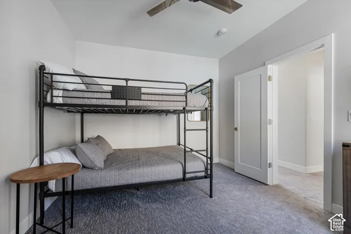 Light gray walls, light gray carpet flooring, white door, and a ceiling fan