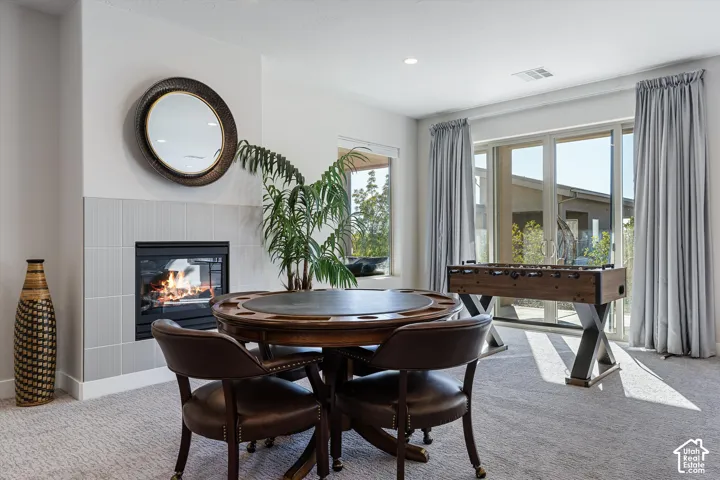 Integrated fireplace with light gray tile surround, large glass sliding doors, additional window, and carpeted flooring