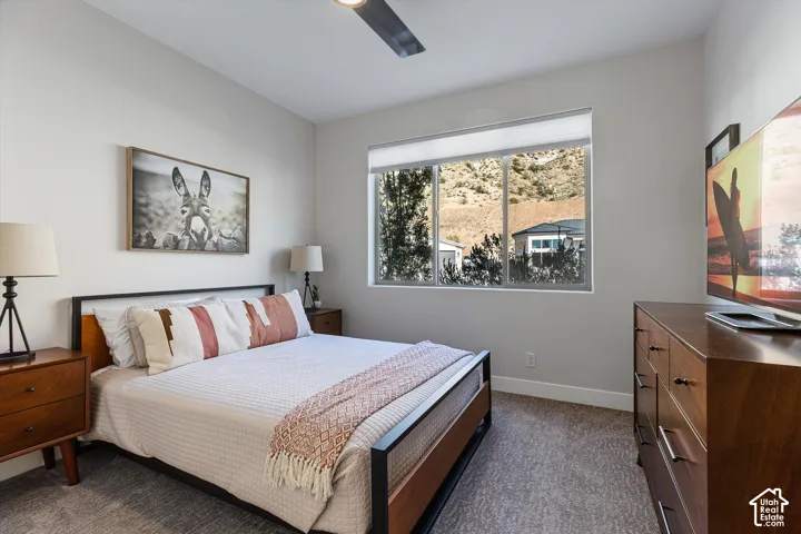 Window with roller shade, wood-finish flooring, and a ceiling fan with integrated lighting