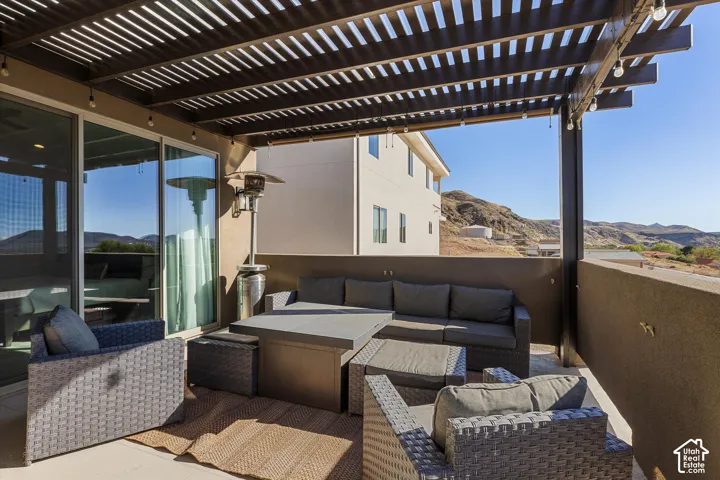 Patio with a slatted pergola, integrated lighting, sliding glass doors, and a partial privacy wall