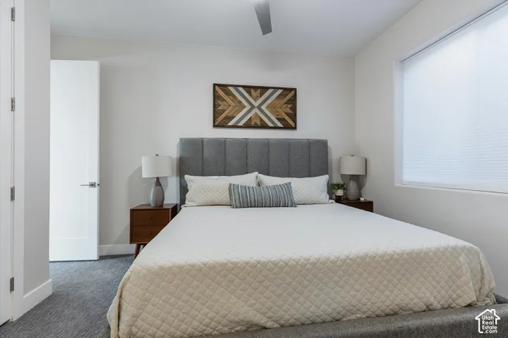 Recessed lighting, ceiling fan, white paneled door, large window with cellular shades, and gray carpeting