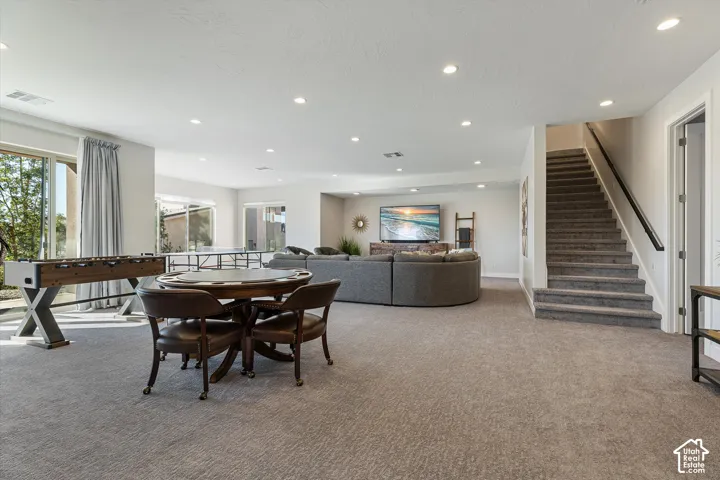 Recessed lighting illuminates a spacious room featuring wall-to-wall carpeting and sliding glass doors