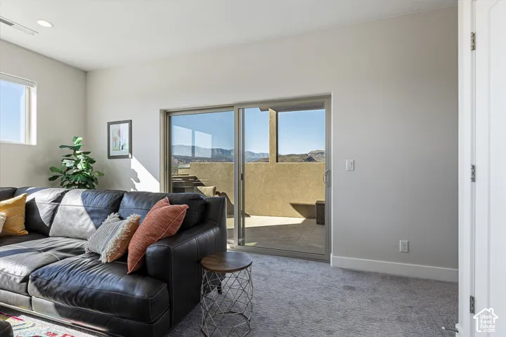 Sliding glass door opening to an outdoor patio with mountain backdrop, recessed ceiling lights, and carpet flooring