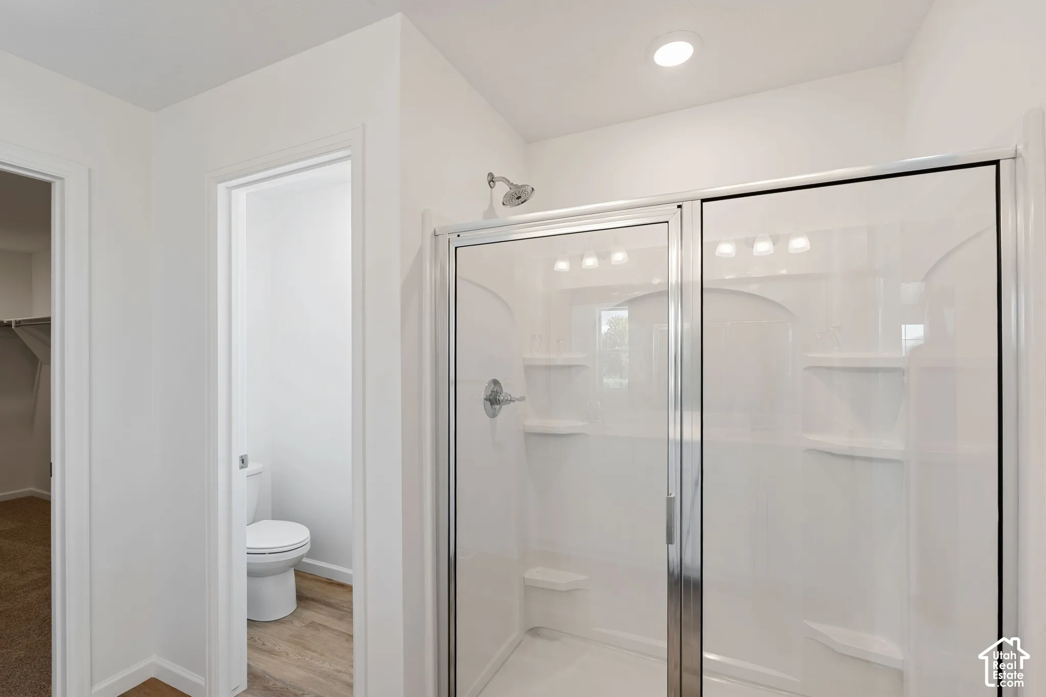 Picture from another model and for example only. Walk-in shower with sliding glass doors, chrome fixtures, recessed lighting, and integrated shelving