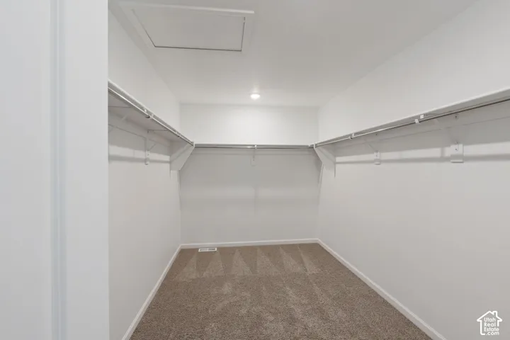 Picture from another model and for example only. Walk-in closet featuring carpet flooring, crisp white walls, and built-in metal shelving with hanging rods