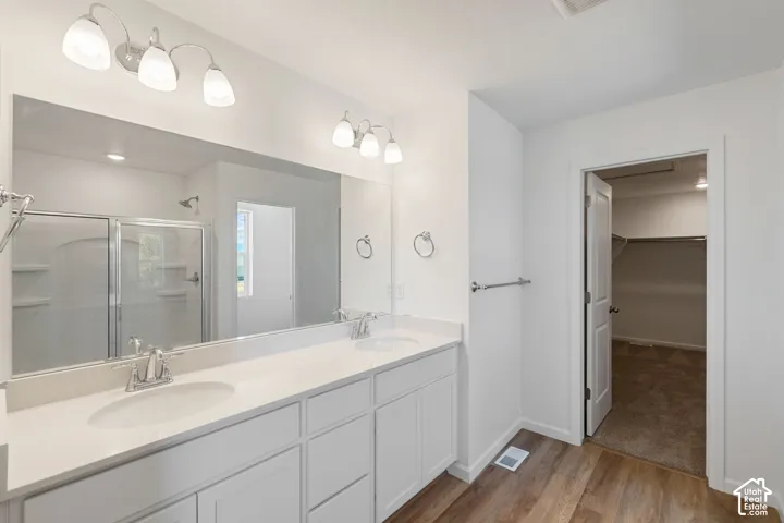 Picture from another model and for example only. Dual vanity with white cabinetry, white countertops, chrome fixtures, and wood-finish flooring
