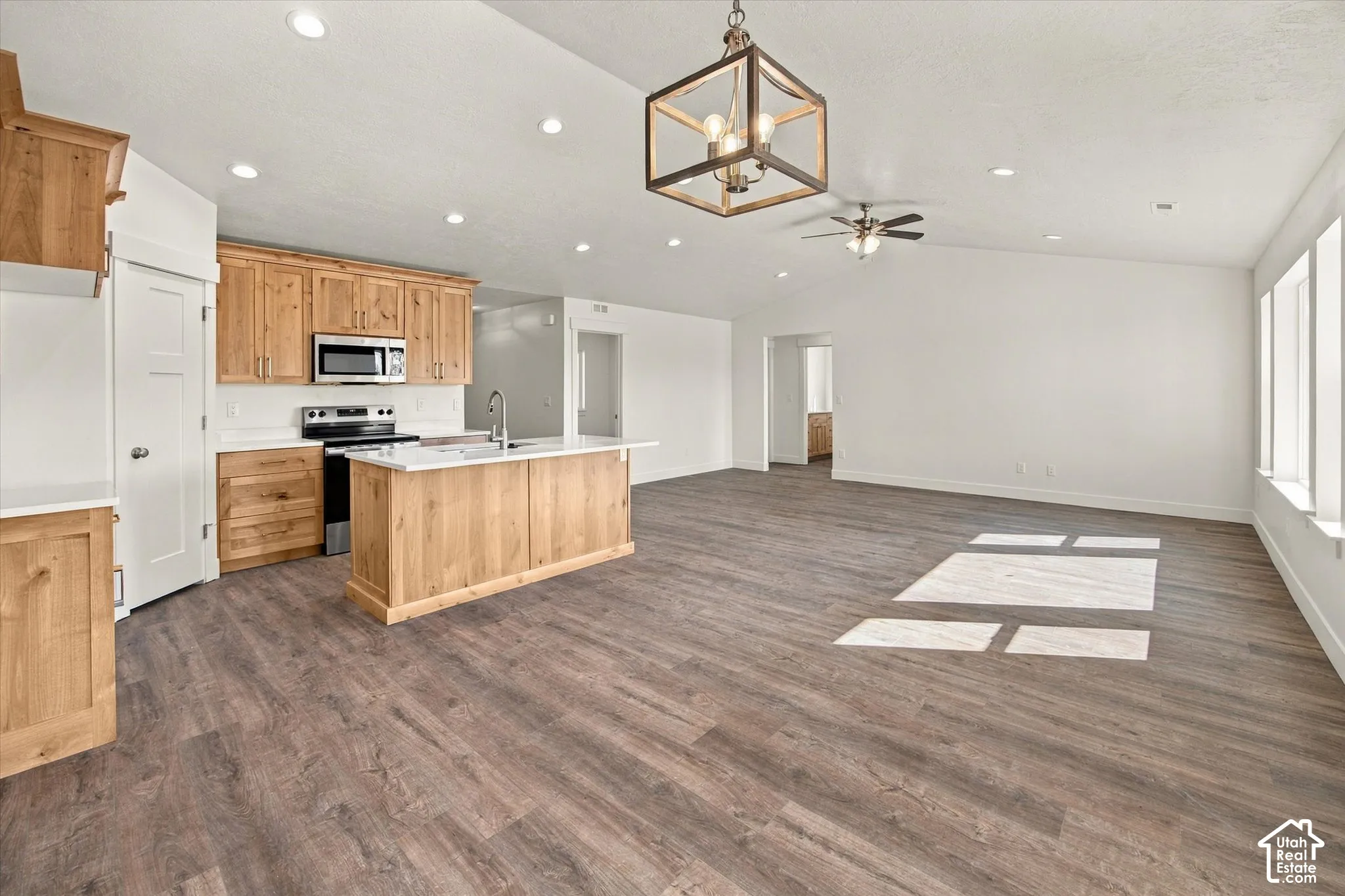 Open-concept living area with wood-finish flooring, vaulted ceilings, and recessed lighting
