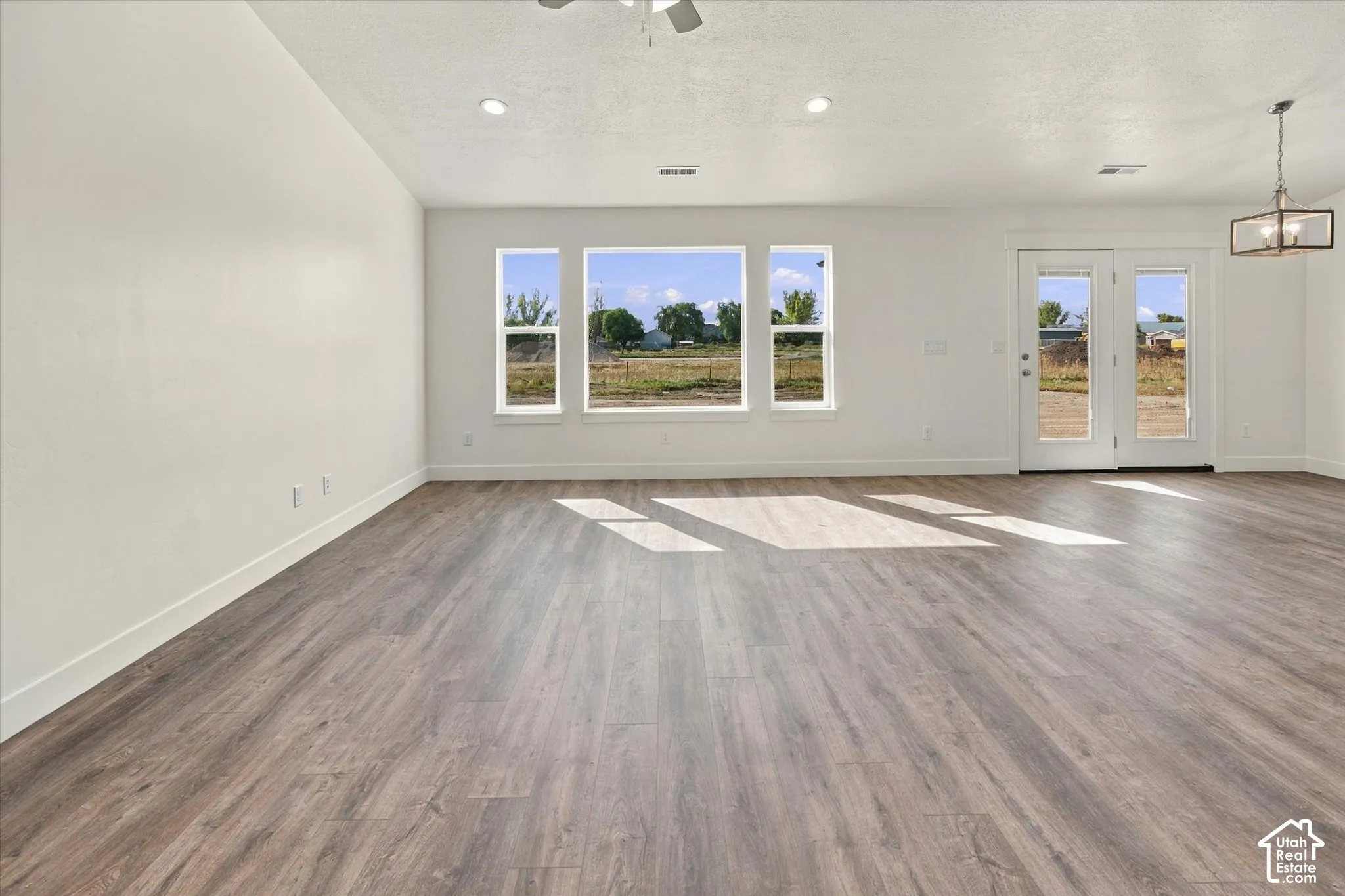 Expansive room with wood-finish flooring, white walls, and multiple windows