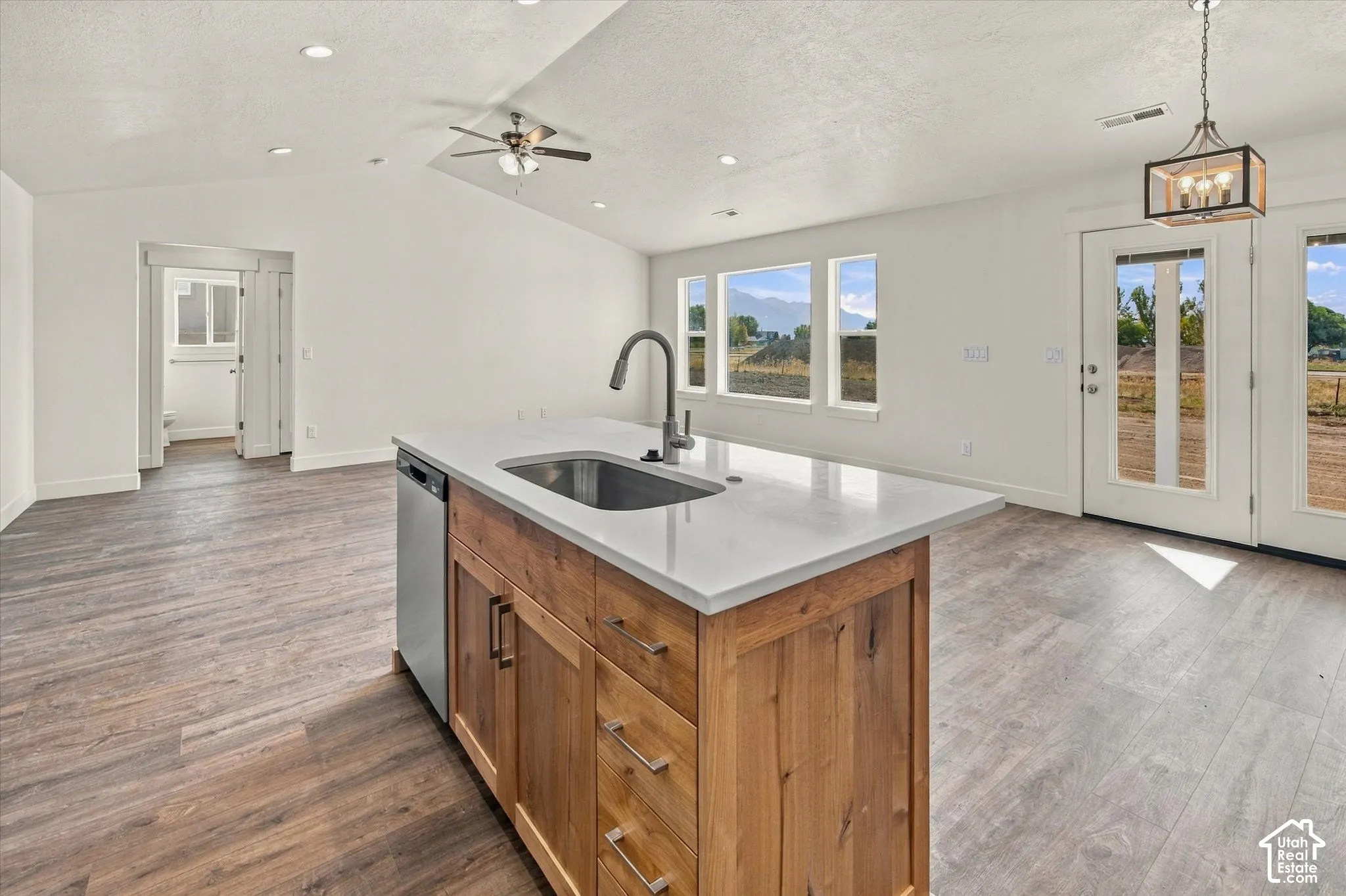 Kitchen island with light-toned countertop, stainless steel sink, and integrated dishwasher