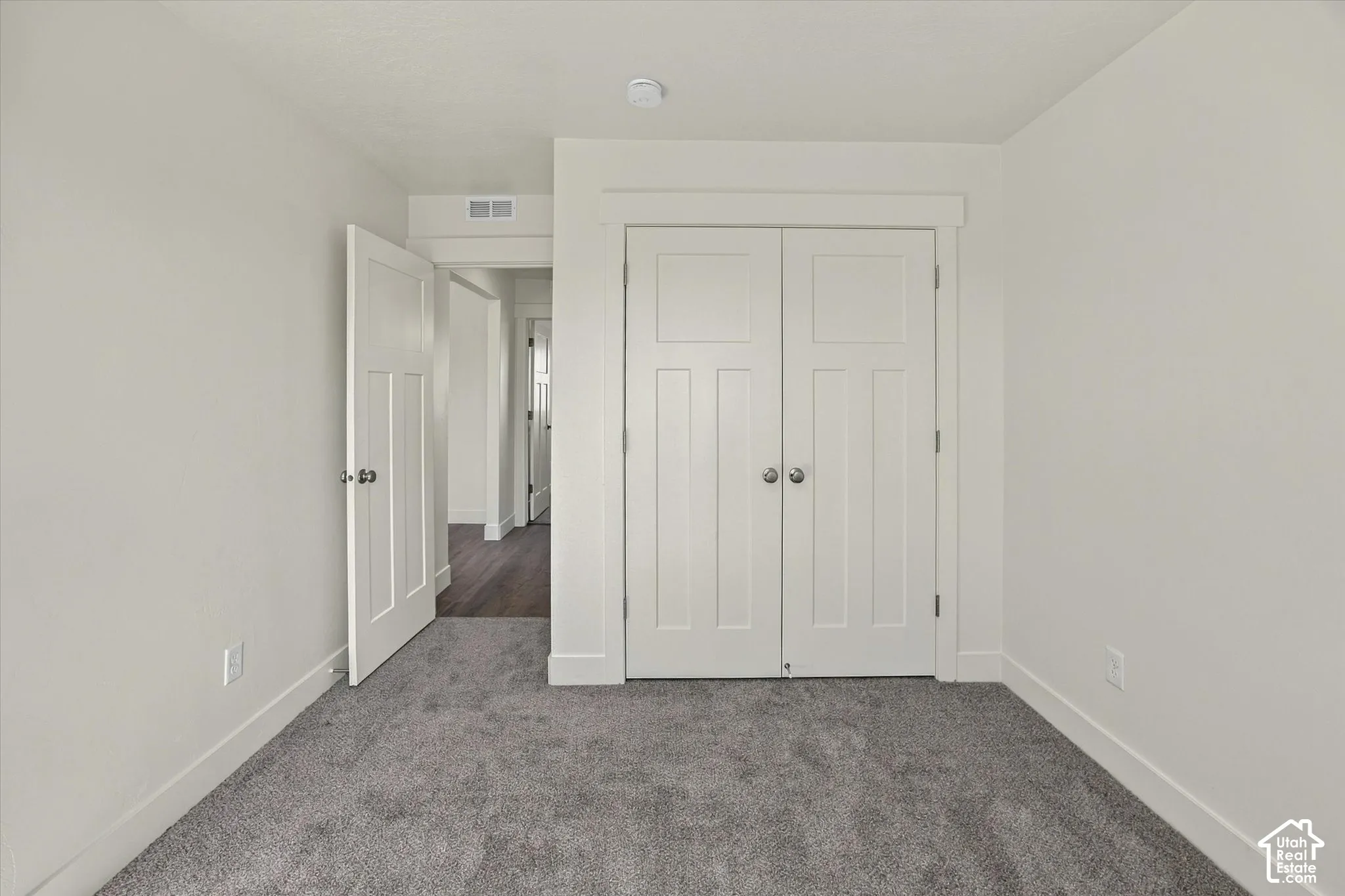 Plush gray carpeting, white painted walls, white paneled doors, and white door trim