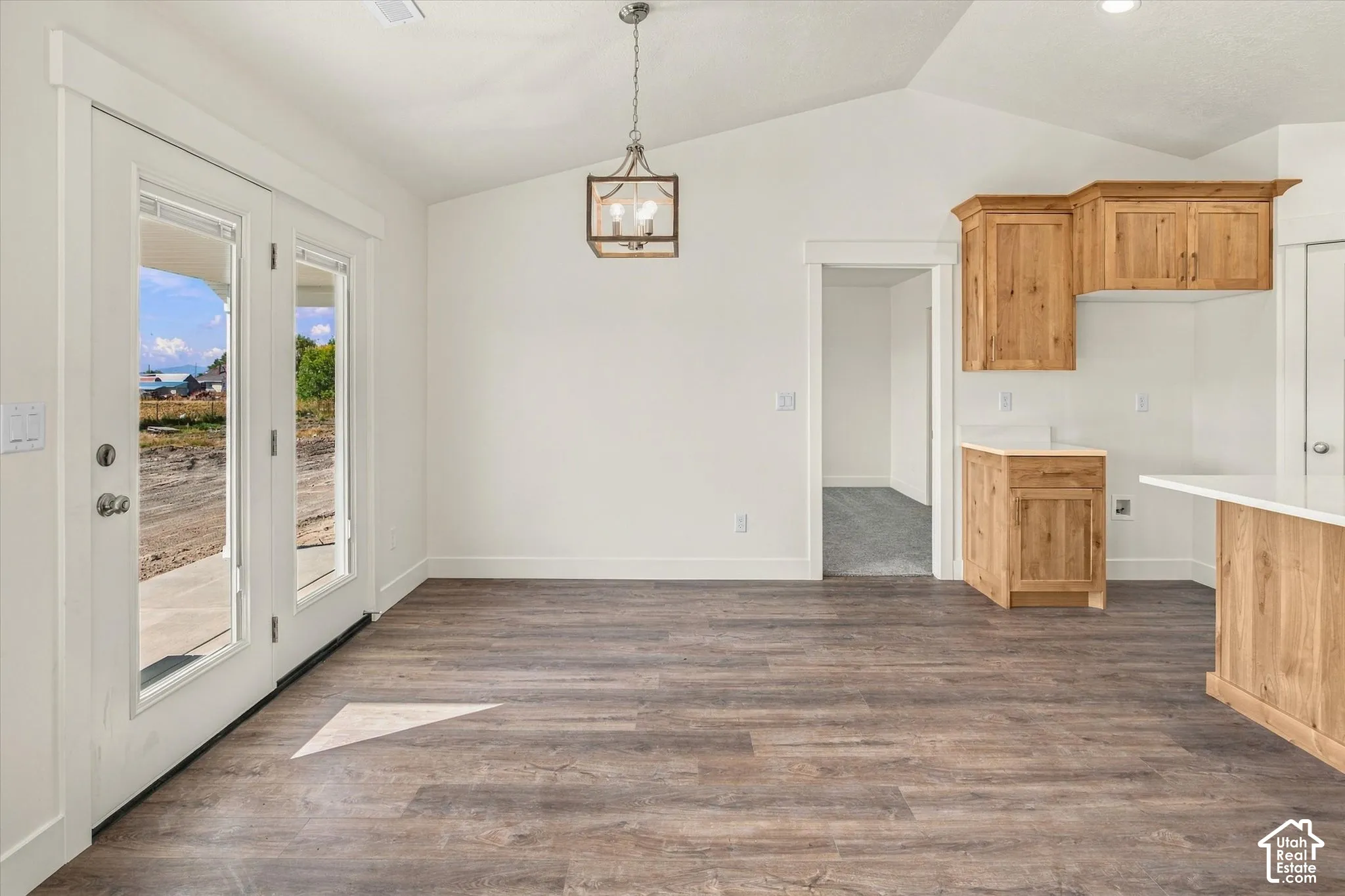 Vaulted ceilings, wood-finish flooring, natural wood cabinetry, pendant lighting, and glass-paneled doors