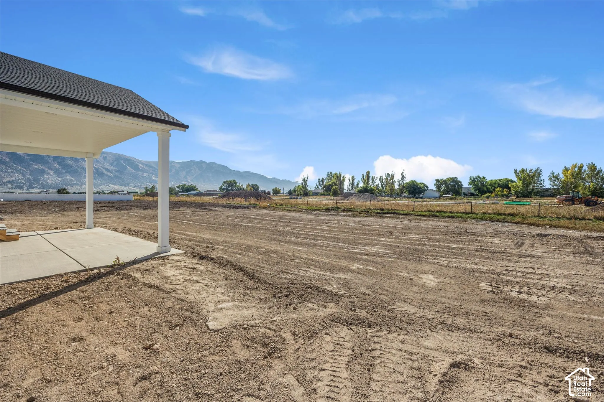 Covered patio with concrete slab, expansive undeveloped land, and a distant mountain range