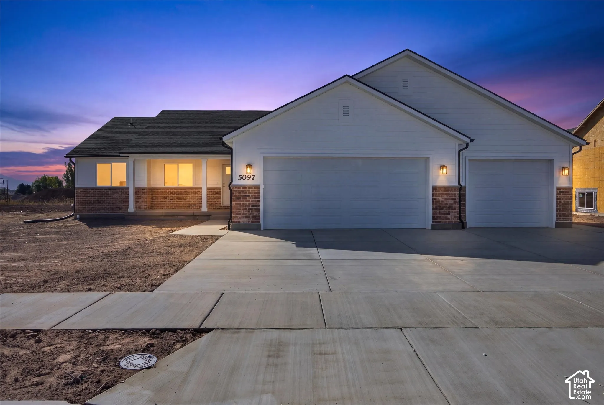 Contemporary exterior with brick and siding accents, featuring an attached two-car garage, a covered front porch with columns, and a concrete driveway