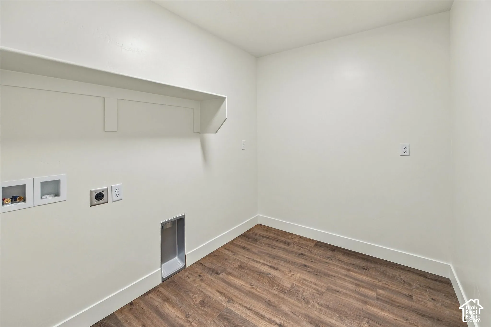 Dedicated utility area featuring a wood-finish floor, built-in shelving, and white walls