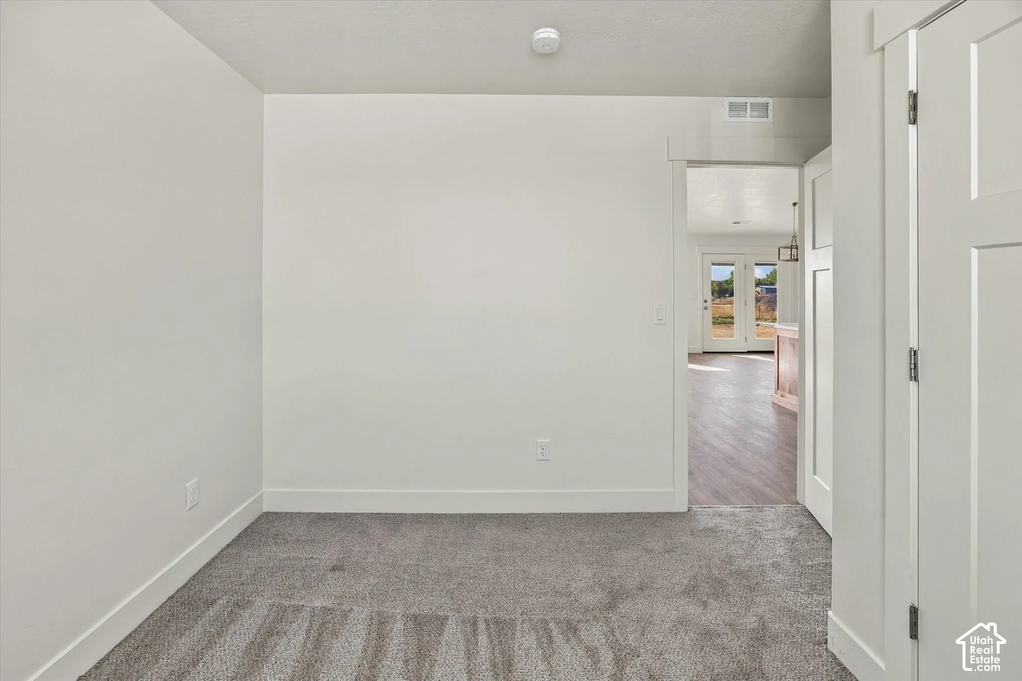 Neutral tone wall paint, gray carpeting, white trim, and white paneled interior doors