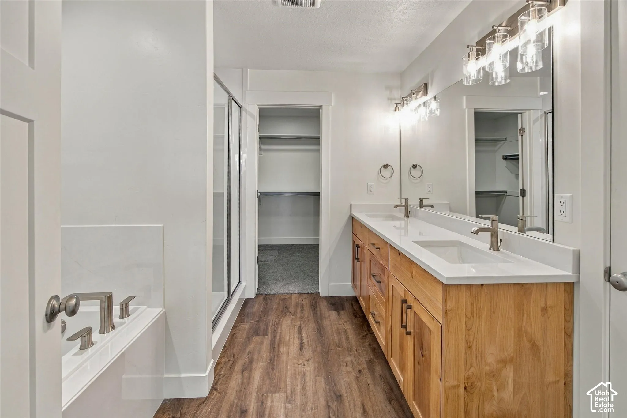 Double vanity with wood-finish cabinetry, white countertops, dual undermount sinks, and brushed nickel fixtures