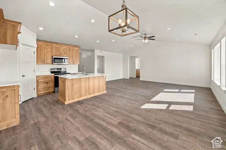 Open-concept living area with wood-finish flooring, vaulted ceilings, and recessed lighting