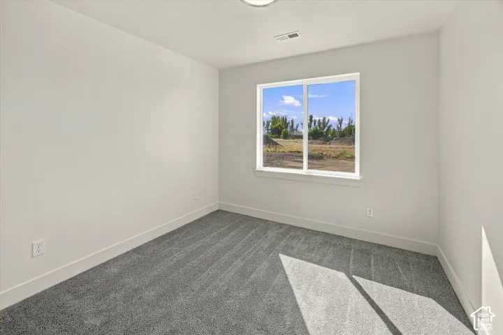 Neutral tone wall paint, gray patterned carpeting, recessed ceiling lighting, and a white framed window