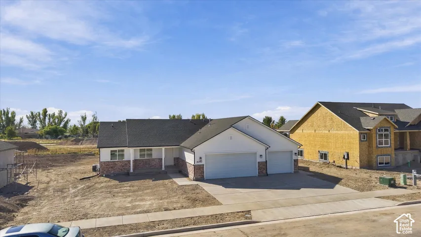 Single-story residence featuring a white exterior, partial brick facade, and a two-car garage