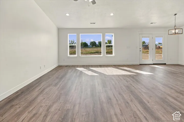 Expansive room with wood-finish flooring, white walls, and multiple windows
