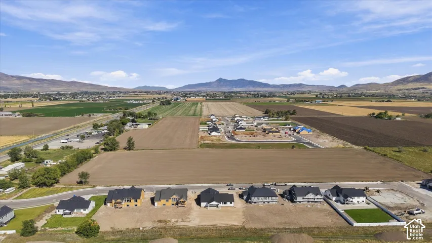 Expansive rural landscape with developing residential areas, surrounded by agricultural fields and distant mountains