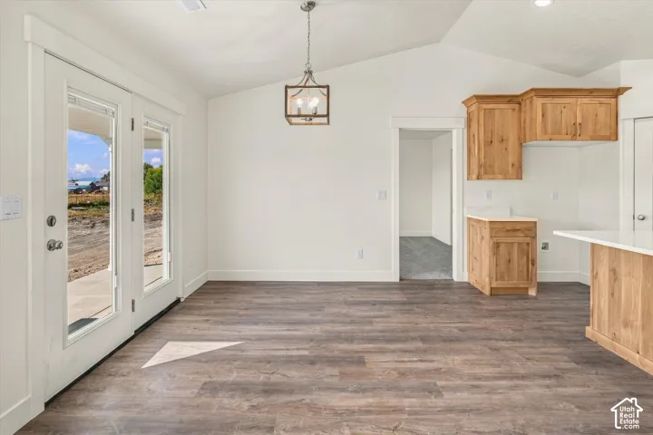 Vaulted ceilings, wood-finish flooring, natural wood cabinetry, pendant lighting, and glass-paneled doors