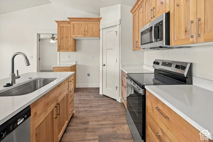 Kitchen featuring wood-finish cabinetry, stainless steel appliances, white countertops, and wood-finish flooring