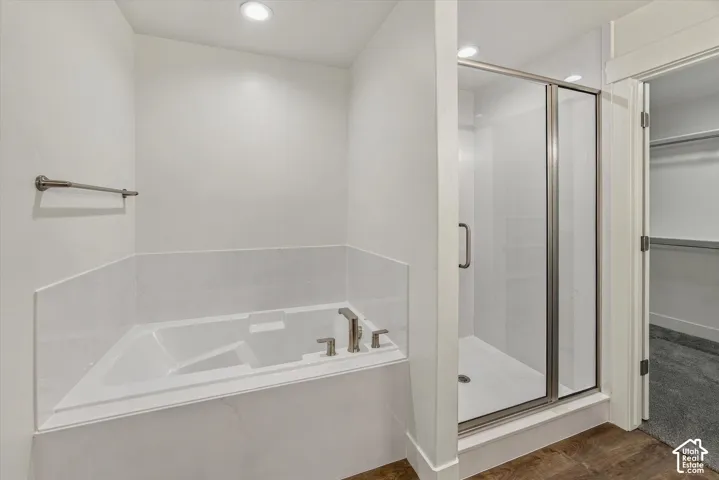 Built-in bathtub with tile surround, glass-enclosed shower, and recessed lighting