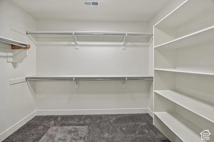 Custom closet system with multiple shelving units, hanging rods, and carpet flooring